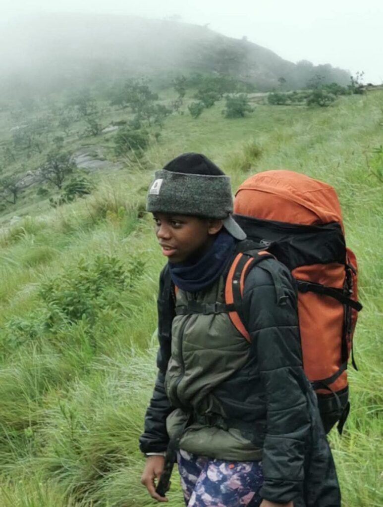 Mia hiking through misty green grassland with an orange backpack