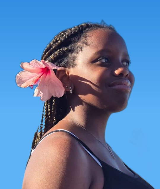 Portrait of Mia with a pink hibiscus flower in her hair against a blue sky